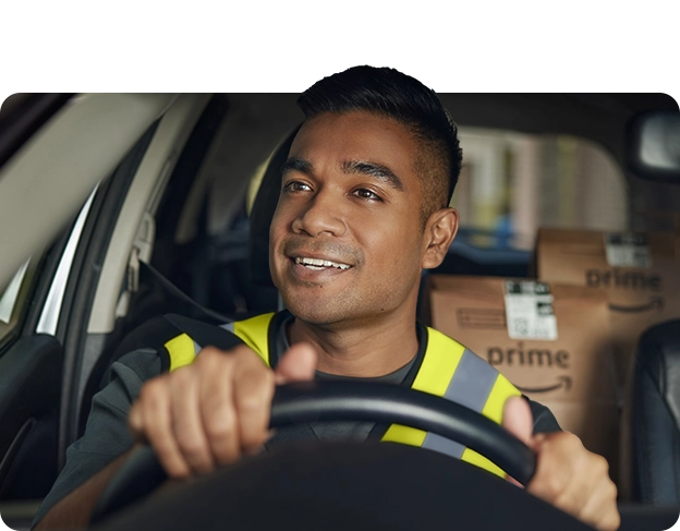 Happy Amazon delivery driver in safety vest sitting in vehicle with packages visible behind him