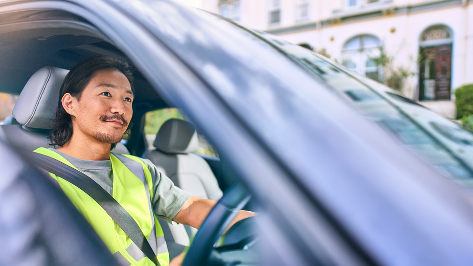 Man in a yellow vest driving a sedan